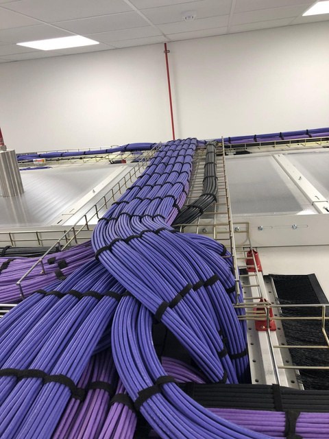 Bundled copper cabling dressed across overhead basket tray