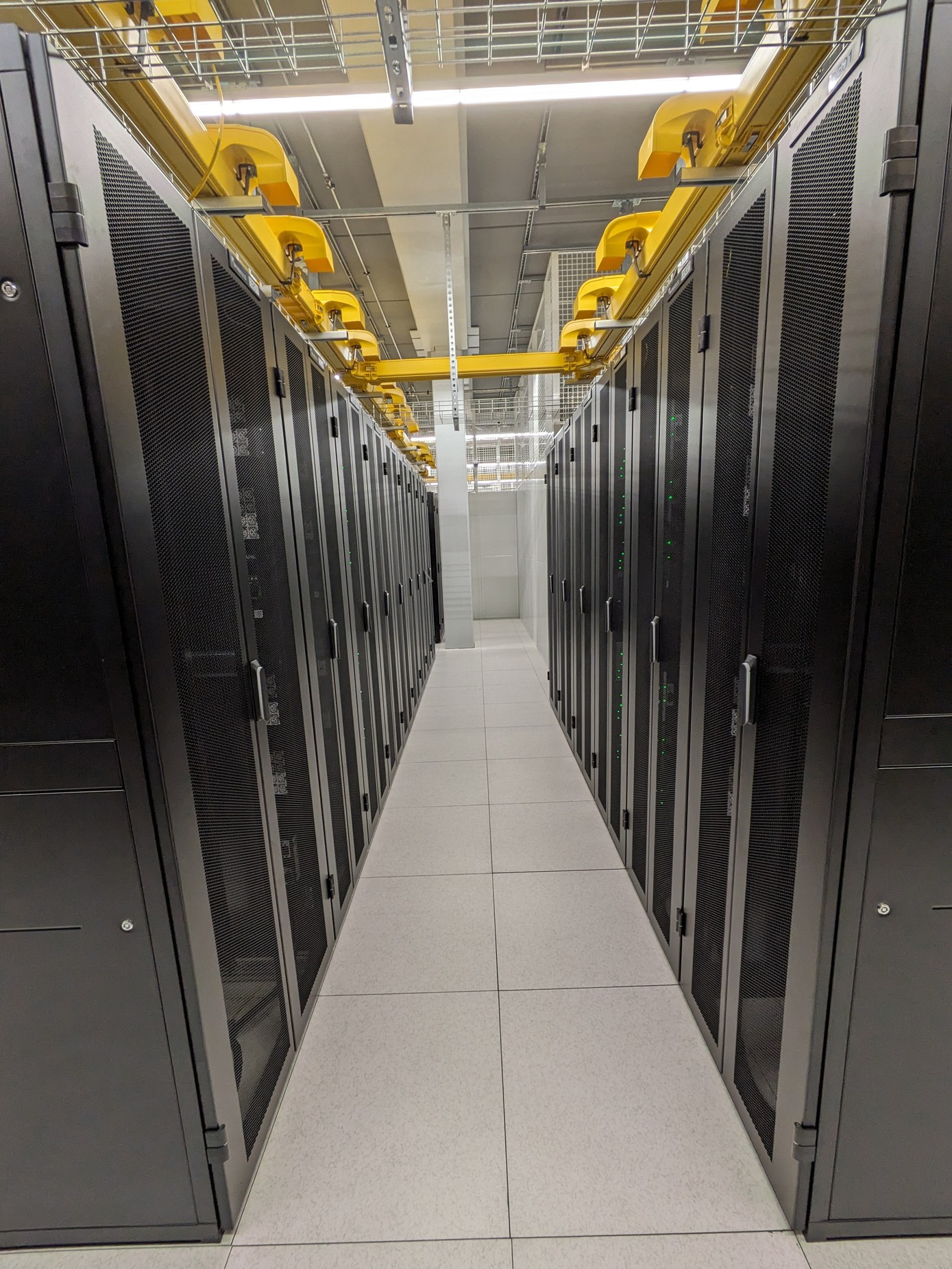 A finished data hall aisle with overhead fibre tray