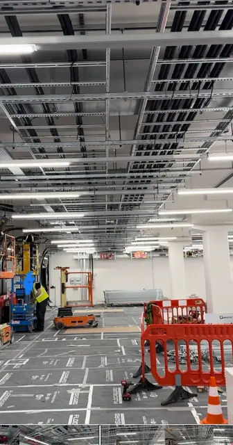 A hall under construction with its containment grid, an access platform and barriers
