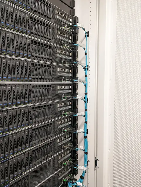 A dense server rack with aqua fibre run down the side