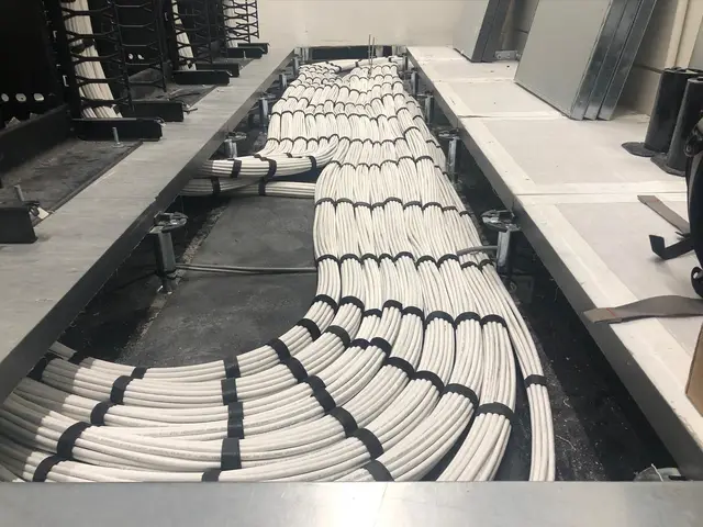 White cable bundles running along an under-floor tray